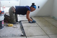 A volunteer lays tile in a homeowner's house.